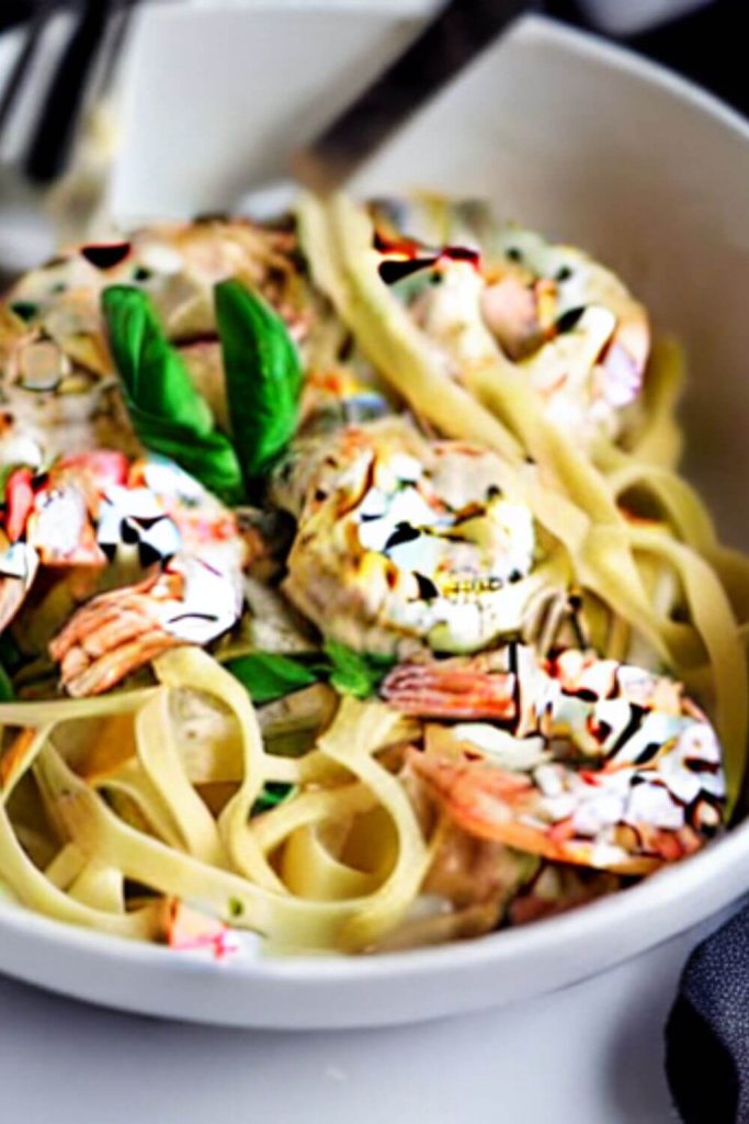 aerial view of white bowl with chicken shrimp carbonara pasta and sauce on white countertop and gray tea towel